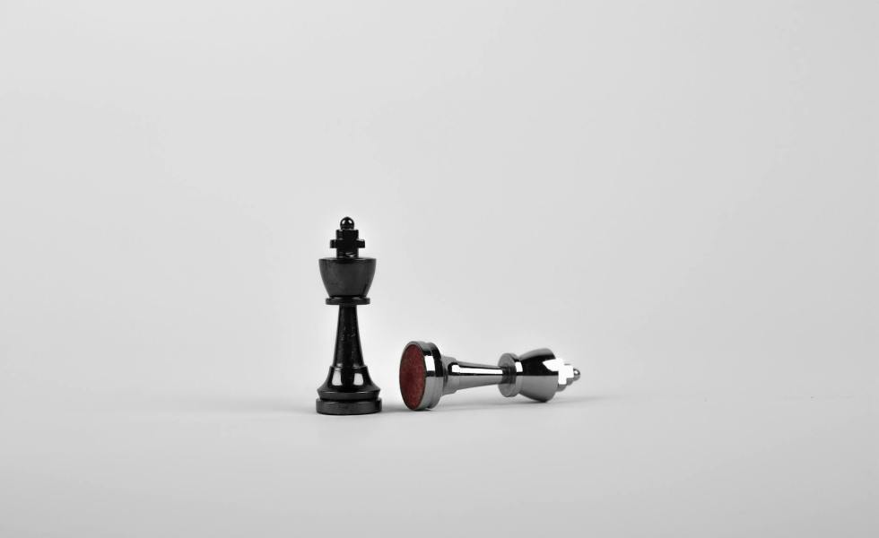 two silver chess pieces on white surface