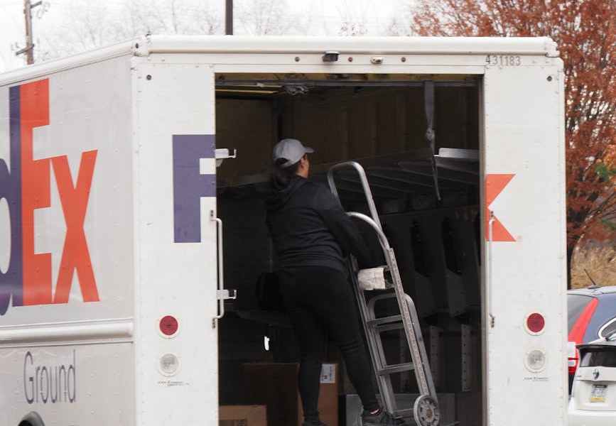 woman standing on the back of a delivery service truck